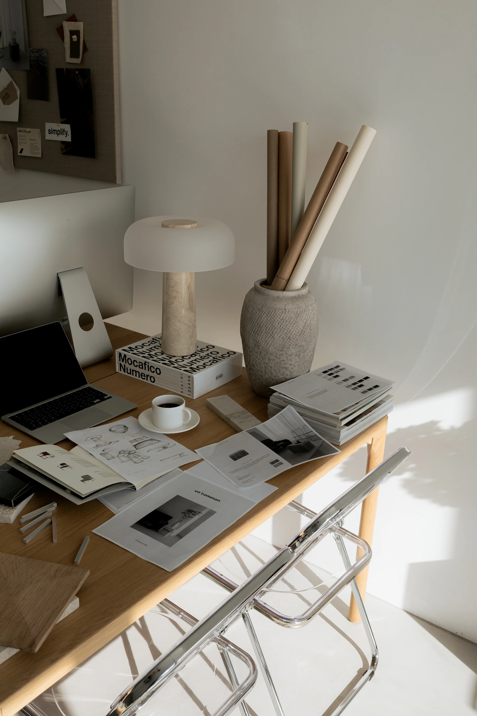 Bureau de designer baigné de lumière naturelle, étuis de plans papier